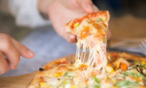 Appetizing close-up of a cheesy pizza slice with toppings, being pulled from a freshly baked pie. - Photo by Cats Coming on Pexels