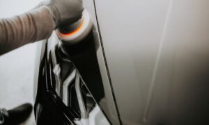 Close-up view of a person polishing a black car using a buffing machine. - Photo by Luke Miller on Pexels
