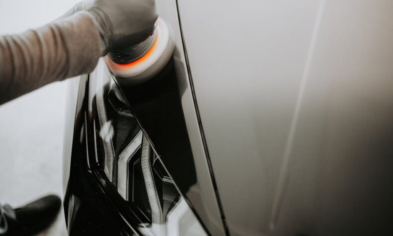 Close-up view of a person polishing a black car using a buffing machine. - Photo by Luke Miller on Pexels